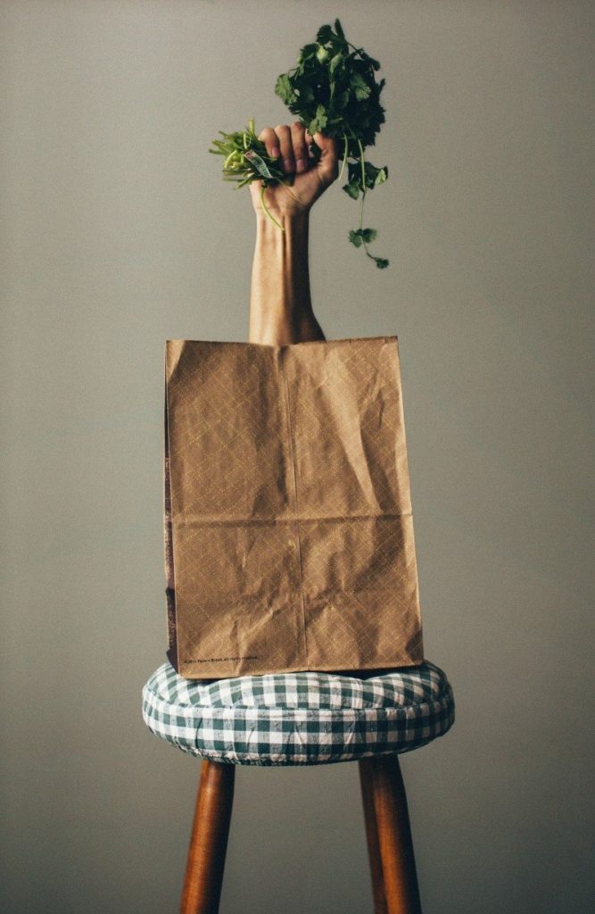 Stool With Paper Bag And Human Hand Holding Green Parsley