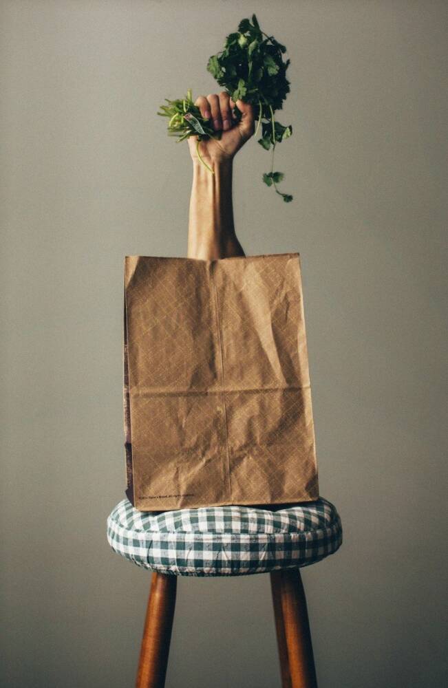 Stool With Paper Bag And Human Hand Holding Green Parsley